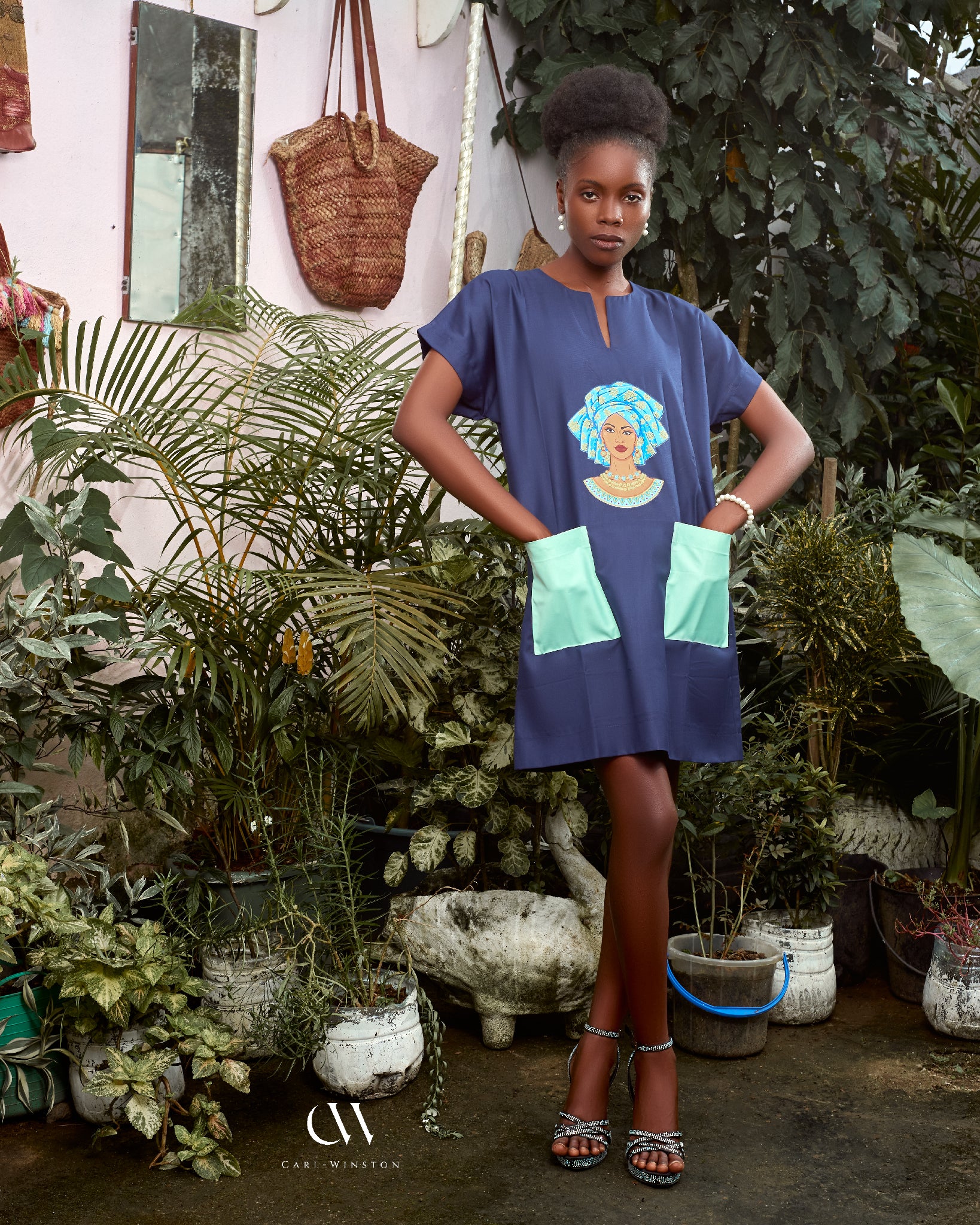 Carl-Winston navy blue African-inspired dress with an intricate print of a woman in traditional headwrap, complemented by light mint green pockets. This culturally rich and stylish dress brings elegance and comfort, ideal for those looking to celebrate heritage with modern flair.