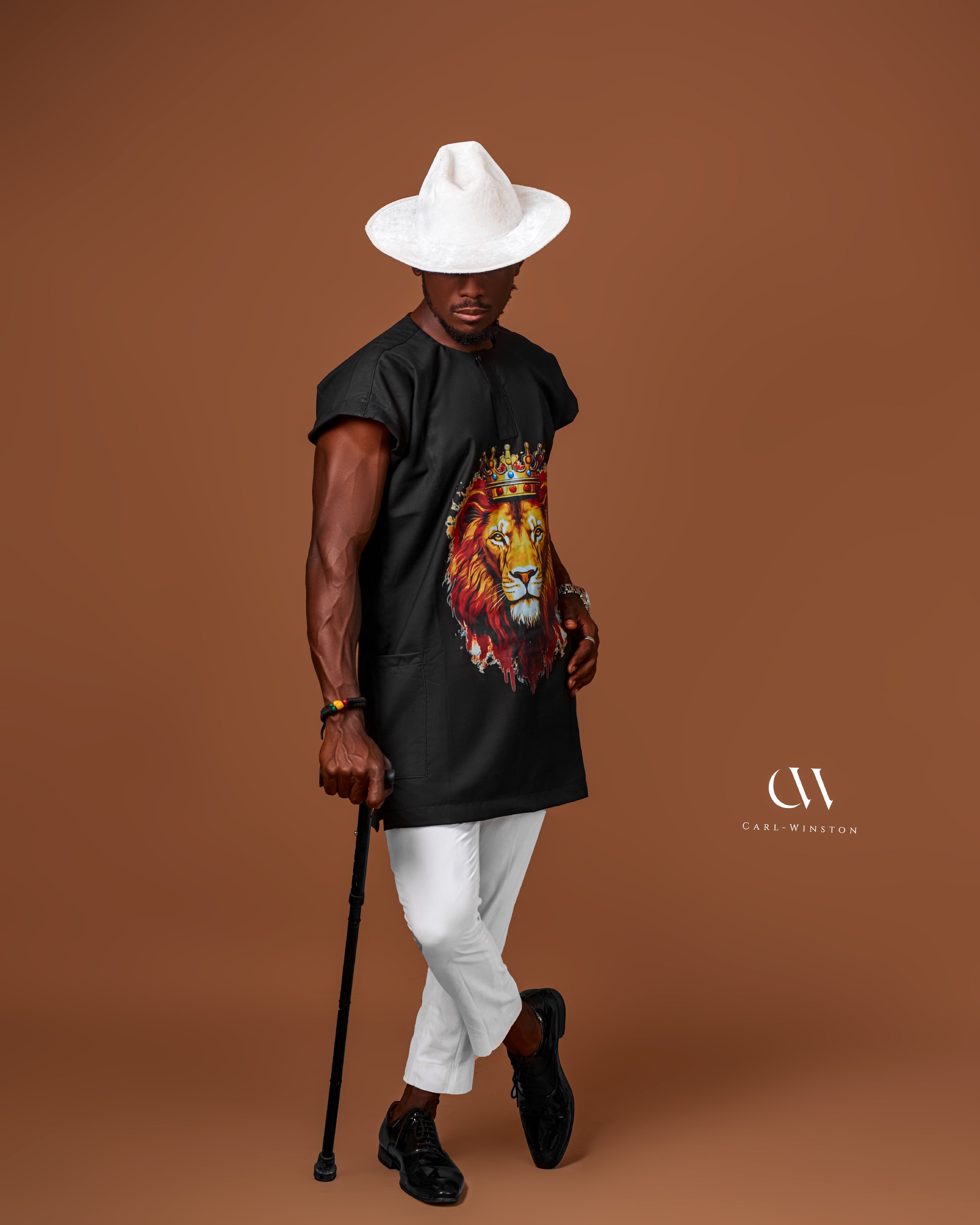 Carl-Winston African-inspired black tunic with lion emblem, paired with a white hat, exuding boldness and elegance in traditional fashion.