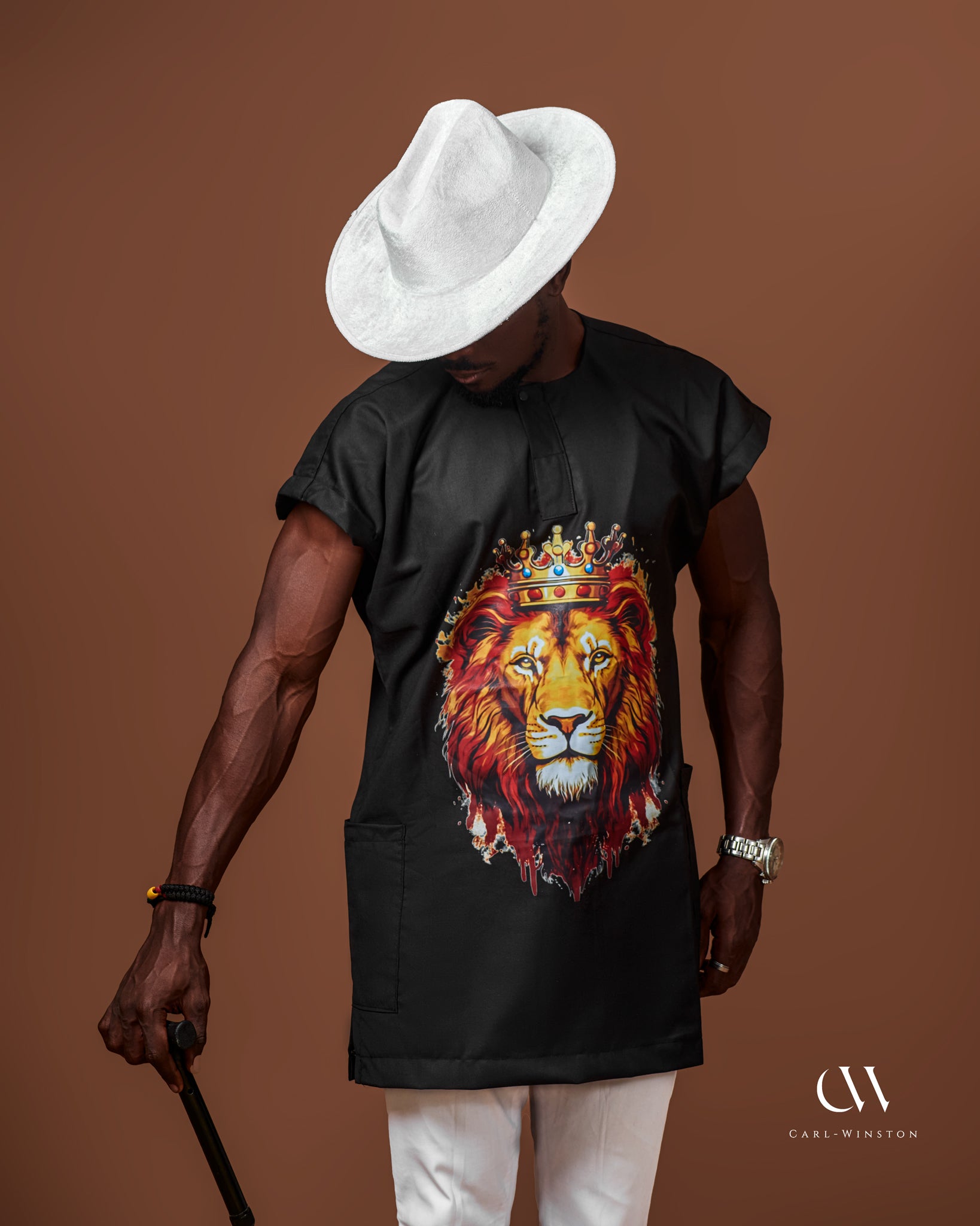 Carl-Winston African-inspired black tunic with lion emblem, paired with a white hat, exuding boldness and elegance in traditional fashion