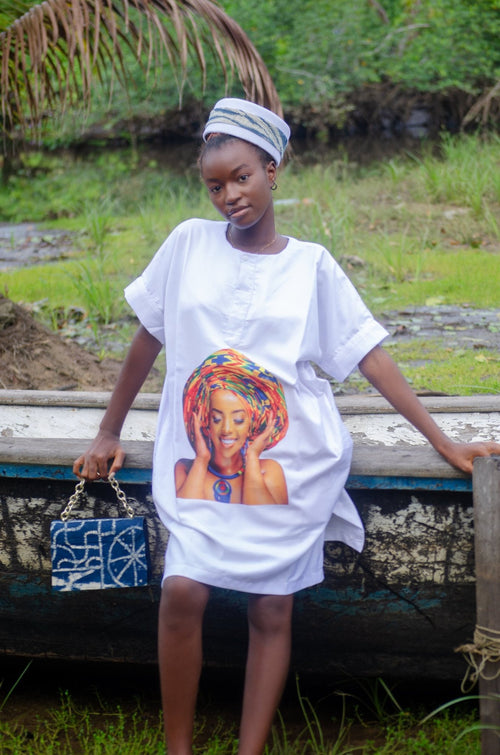 African woman wearing a blue dress vibrant graphic print of a smiling woman in a traditional head wrap, seated with a matching blue patterned handbag  African-inspired fashion with cultural and artistic flair Carl-Winston