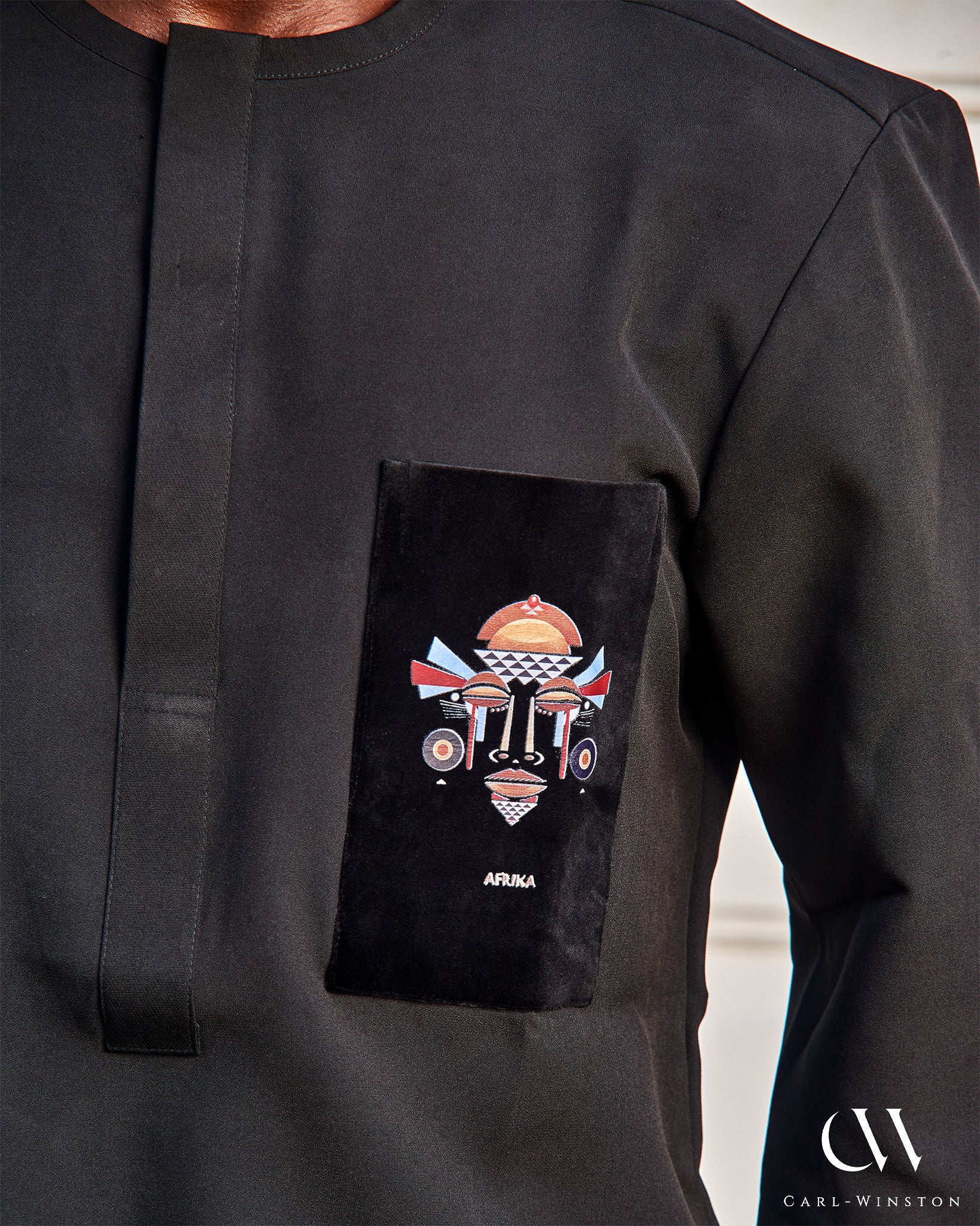 Close-up of the black velvet chest pocket showing intricate embroidery of an African mask and the word “AFRIKA”