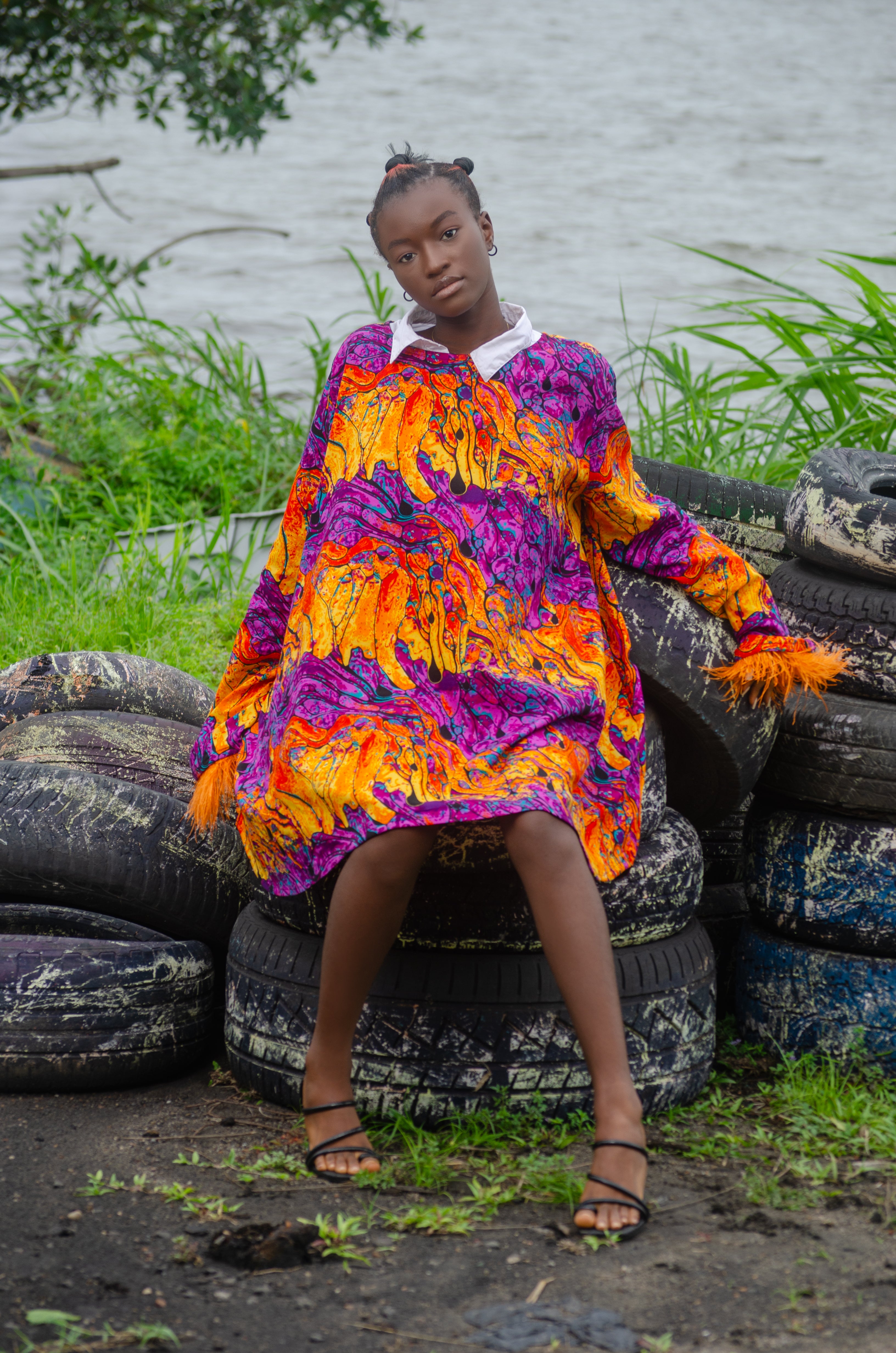 African woman wearing a colorful Carl-Winston oversized dress with bold orange purple yellow abstract patterns African attire exudes vibrant energy and stylecultural heritage with a modern twist