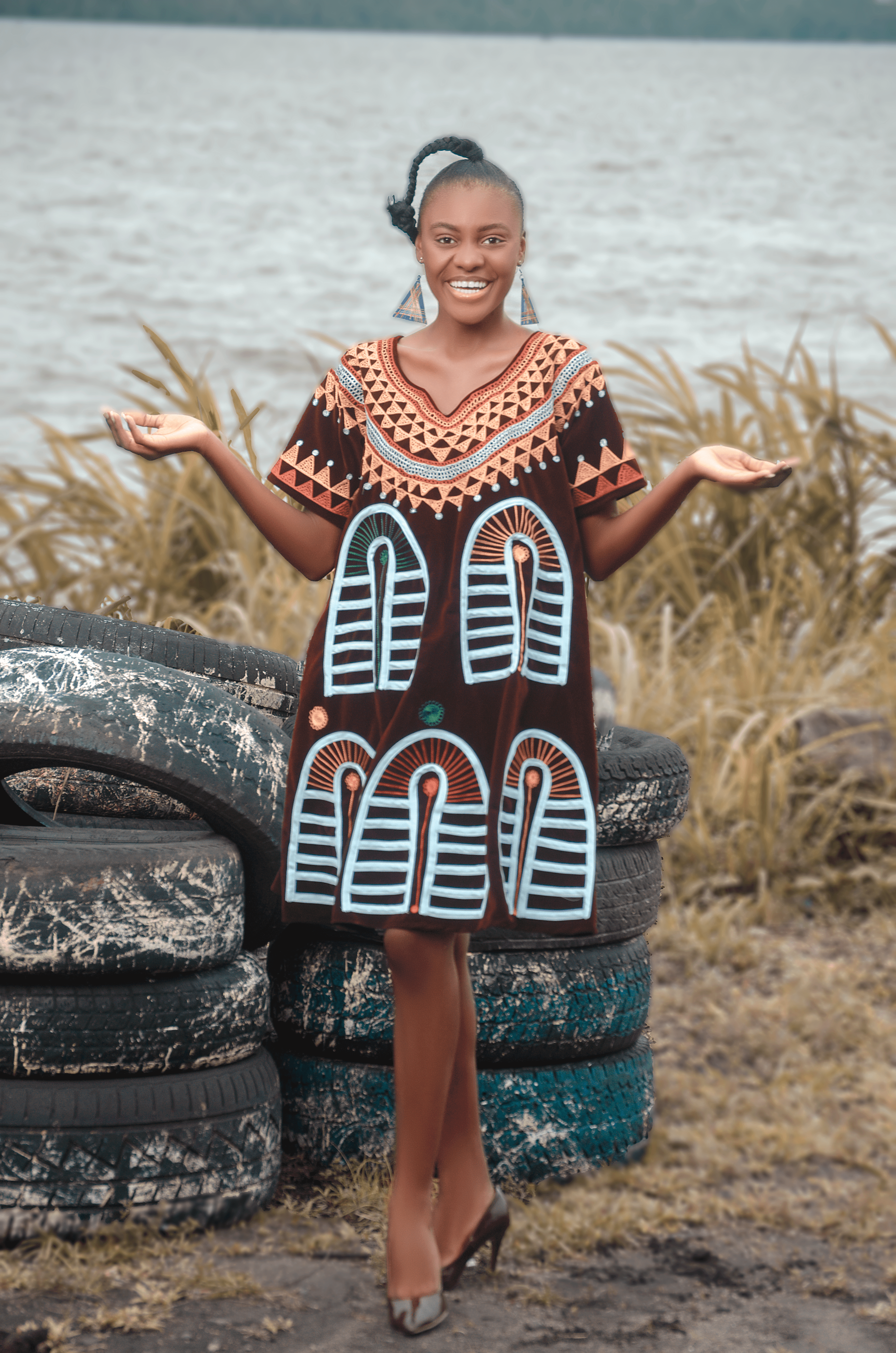 African woman wearing a traditional brown embroidered dress with vibrant blue and orange tribal patternsAfrocentric fashion and heritage Carl-Winston