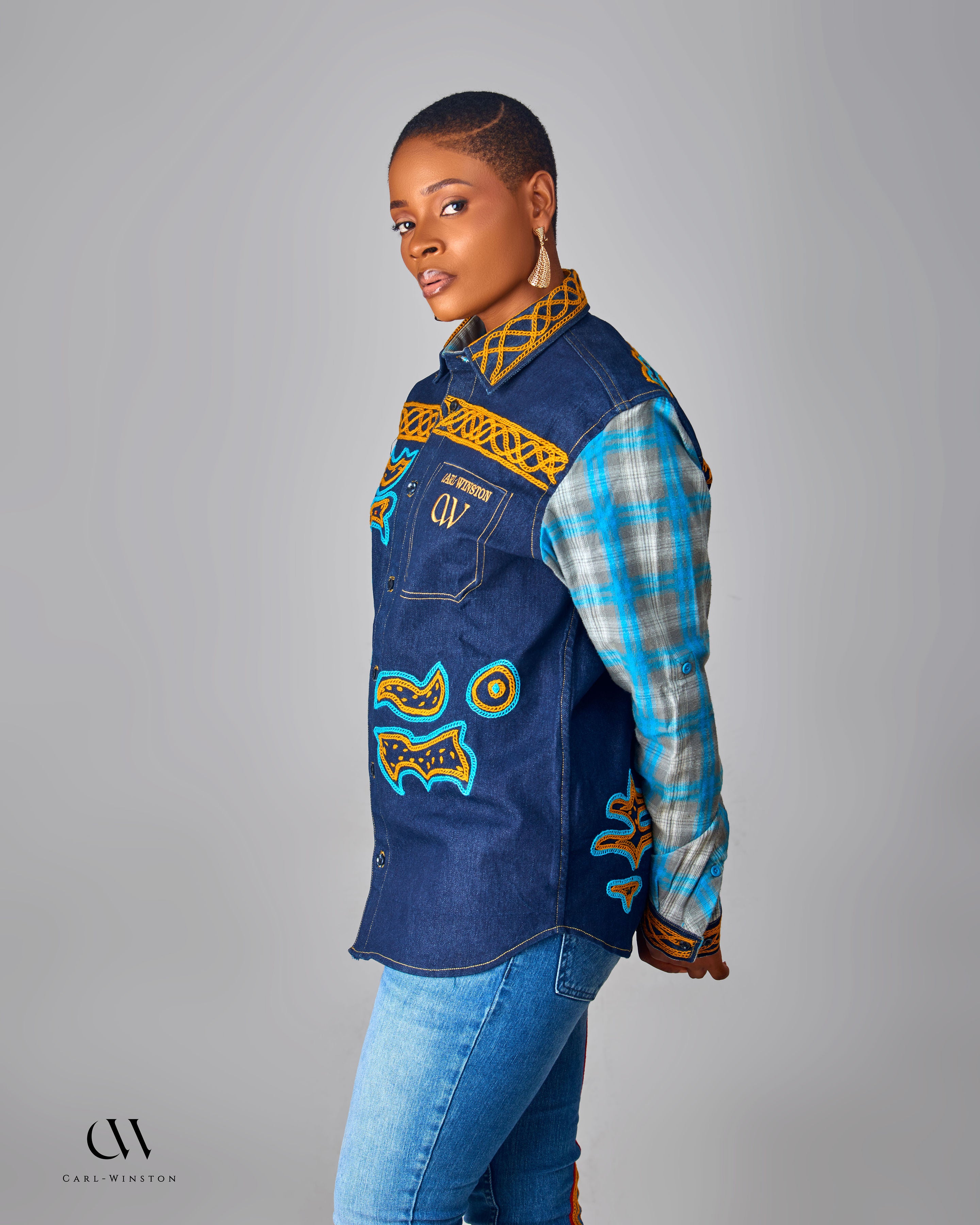 Woman wearing a denim jacket with colorful patterns on a gray background