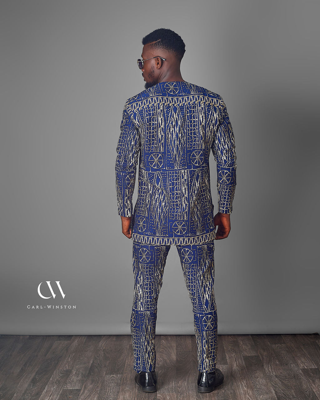 Man wearing a blue and white patterned suit standing against a gray background