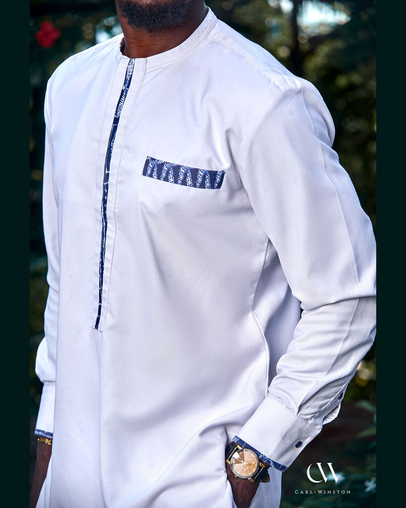 Close-up of the Bamileke Ceremony Kaftan showcasing detailed Bamileke fabric along the collar, chest pocket, and sleeve cuffs on crisp white cotton.