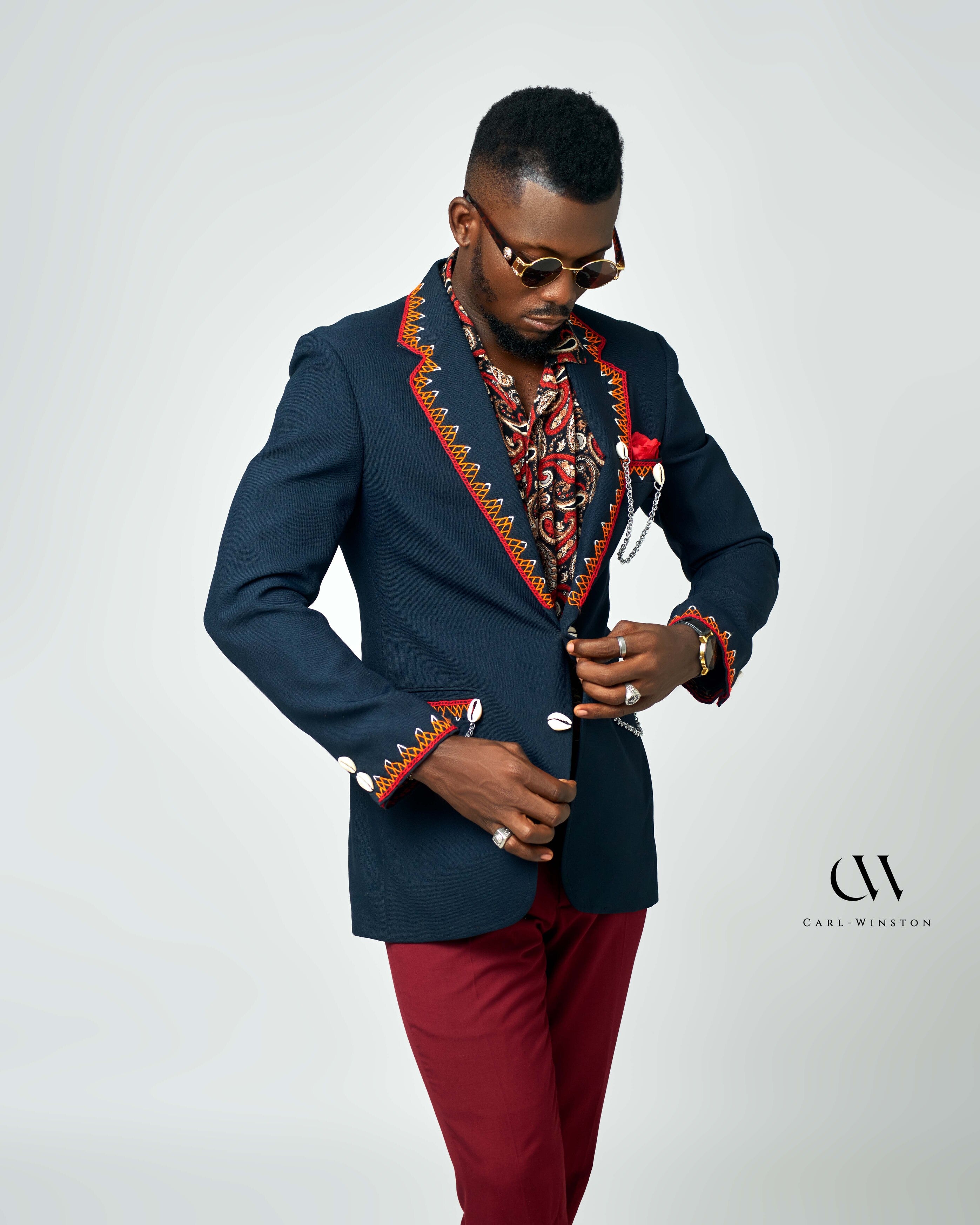 A paisley-print men’s shirt in vibrant colors, styled with a navy blazer and maroon pants for a bold and sophisticated look by Carl-Winston.