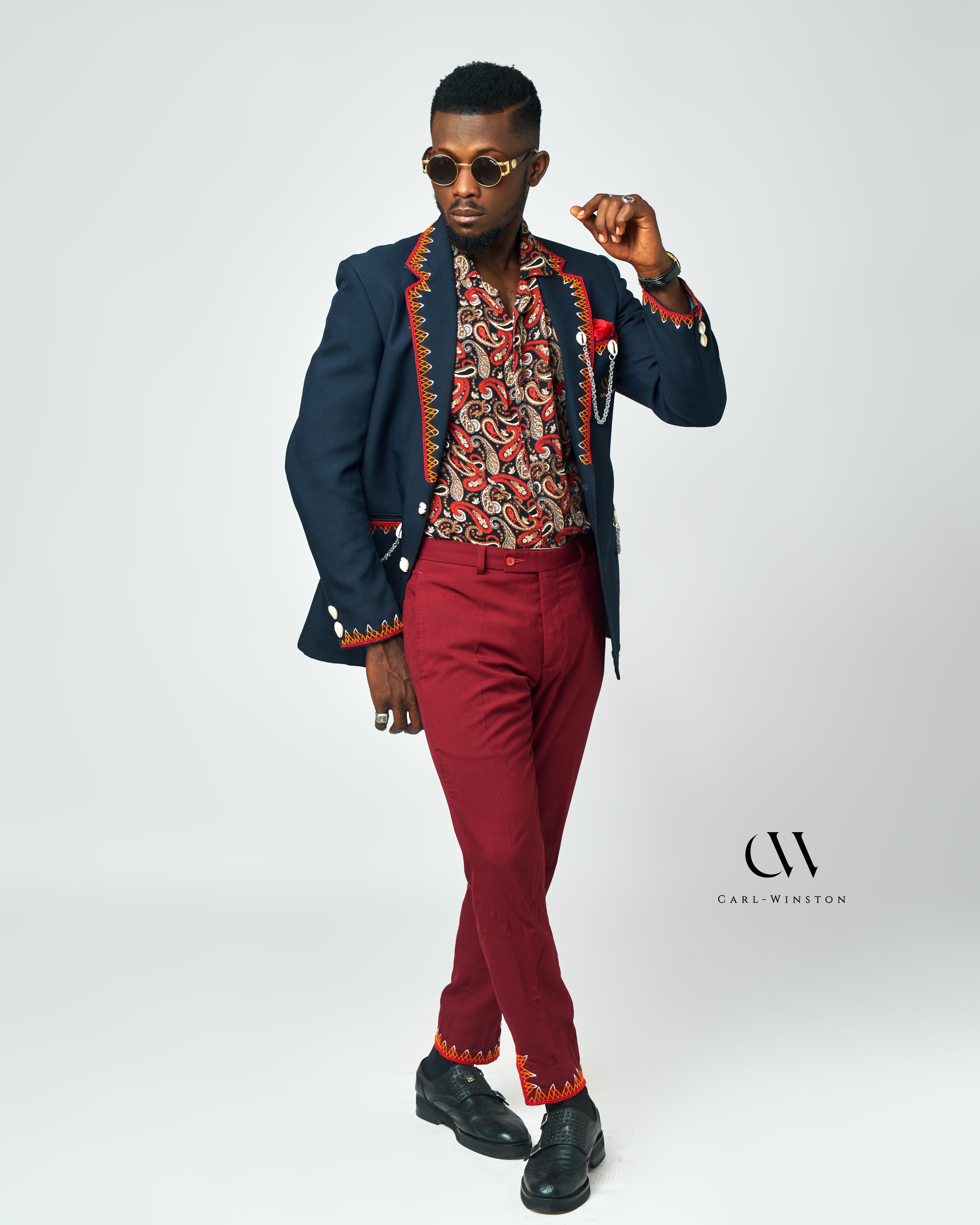 A paisley-print men’s shirt in vibrant colors, styled with a navy blazer and maroon pants for a bold and sophisticated look by Carl-Winston.
