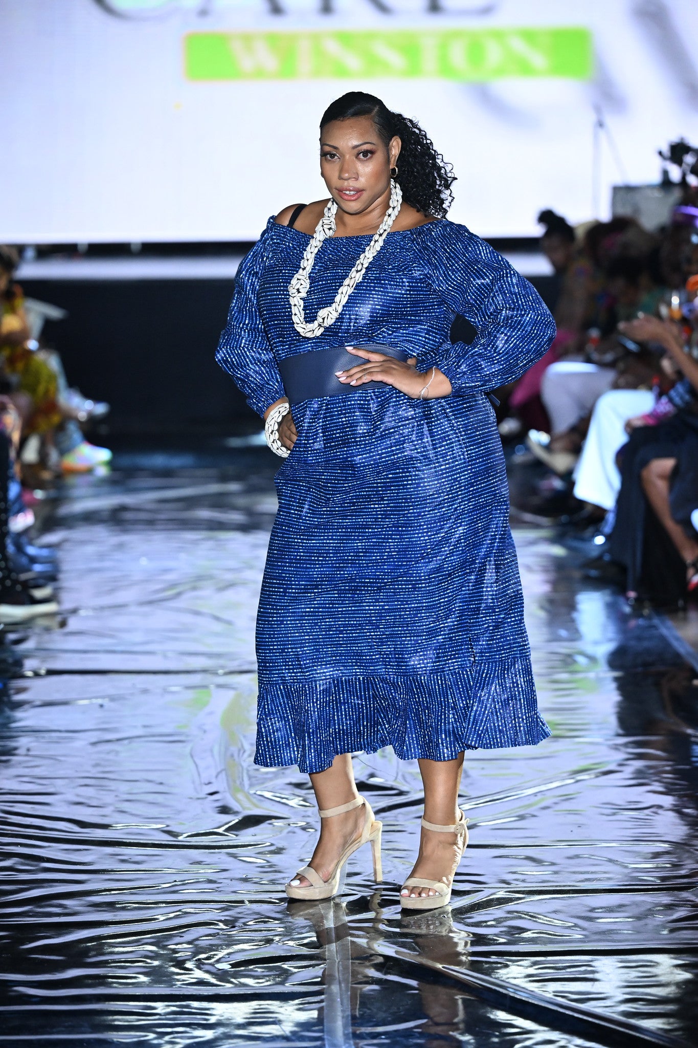 The Royal Indigo Heritage Dress is a tribute to African craftsmanship—crafted from indigo-dyed fabric and styled with cultural cowrie accents. Worn at Ankara Fest, this look celebrates strength, beauty, and authenticity. 